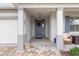 Covered entryway with a blue door, brick flooring, and decorative planters at 8916 Sw 78Th Street Rd, Ocala, FL 34481