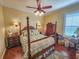 Charming bedroom with a wooden four-poster bed, hardwood floors, and a ceiling fan at 12152 Se 91St Ave, Summerfield, FL 34491