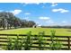 Pasture with wooden fence, trees, and a white barn in the distance at 8544 Nw 160Th Ave, Morriston, FL 32668