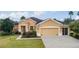 Tan one-story house with a two-car garage and manicured lawn at 9948 Sw 69Th Ln, Ocala, FL 34481
