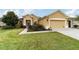 Tan house with a two-car garage and a grassy yard at 9948 Sw 69Th Ln, Ocala, FL 34481