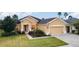 Tan house with two car garage and manicured lawn at 9948 Sw 69Th Ln, Ocala, FL 34481