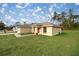 House's side view showcasing a tan exterior, red-trimmed windows, and a spacious green lawn at 16690 Sw 50Th Ave, Ocala, FL 34473