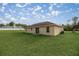 Backyard view of a single-story home showcasing a tan exterior, sliding glass doors, and a grassy backyard at 16690 Sw 50Th Ave, Ocala, FL 34473