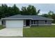 Newly constructed home with a gray exterior, white garage door, and grassy yard at 4073 Se 136 Pl, Summerfield, FL 34491