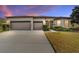 House exterior at dusk, three-car garage, and well-lit landscaping at 9733 Sw 74Th Pl, Ocala, FL 34481