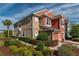 Tan and orange two-story townhome with attached garage and lush landscaping at 4950 Sw 45Th Cir, Ocala, FL 34474