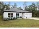 White house with gray roof and landscaping; serene wooded setting at 6366 Sw 153Rd Lane Rd, Ocala, FL 34473