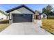 Modern single-story home with gray exterior, black garage door, and a small front yard at 13 Cedar Tree Run, Ocala, FL 34472