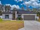 Home with light gray siding, dark gray roof, landscaping, and attached garage at 15720 Sw 19Th Ter, Ocala, FL 34473
