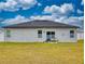 Rear view of a house with a dark roof, white walls, and a grassy backyard at 15720 Sw 19Th Ter, Ocala, FL 34473