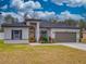 Single-story home featuring gray exterior, landscaping, and a paved driveway at 15720 Sw 19Th Ter, Ocala, FL 34473