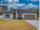 Exterior elevation of a single-story gray house with landscaping and a two-car garage at 15720 Sw 19Th Ter, Ocala, FL 34473