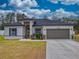 House exterior with gray siding, dark roof, landscaped yard, and two-car garage at 15720 Sw 19Th Ter, Ocala, FL 34473