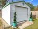 A white garage with green trim, roll-up door and potted trees at 26 Hemlock Cir, Ocala, FL 34472