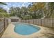 A kidney-shaped pool with a wooden fence and surrounding trees at 6780 Nw 60Th St, Ocala, FL 34482