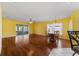 Spacious living room with yellow walls, wood flooring, and a dining area at 9767 Sw 92Nd Place Rd, Ocala, FL 34481