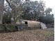 Metal outbuilding with a partially damaged roof sits behind a wooden fence at 18695 Ne 5Th Terrace Rd, Citra, FL 32113