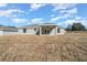 Backyard view of a gray house with a covered patio and large grassy area at 281 Locust Pass, Ocala, FL 34472