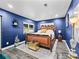 Spacious bedroom with a king-size bed, dark blue walls, and a leopard print rug at 3505 Ne 97Th Street Rd, Anthony, FL 32617