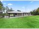Ranch-style home with metal roof, extended patio, and large grassy yard at 3505 Ne 97Th Street Rd, Anthony, FL 32617