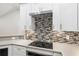 Modern kitchen with white cabinets, stainless steel appliances, and mosaic backsplash at 39926 Parkinsonia St, Lady Lake, FL 32159