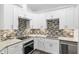 Modern kitchen with white cabinets, stainless steel appliances, and mosaic backsplash at 39926 Parkinsonia St, Lady Lake, FL 32159