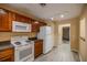 Kitchen with wood cabinets, white appliances, and view into garage at 2505 Se 18Th Cir, Ocala, FL 34471