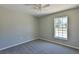 Bright bedroom with grey carpet, ceiling fan, and large window at 115 Guava Place Dr, Ocklawaha, FL 32179