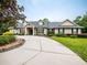 Tan one-story house with a gray roof, landscaping, and a large driveway at 1945 Sw 40Th Pl, Ocala, FL 34471