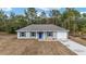 Newly built gray house with blue door and two-car garage at 22043 Sw Rainbow Lakes Blvd, Dunnellon, FL 34431