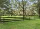 Open pasture with black rail fencing, lush grass, and mature trees at 10502 Se 29Th Ave, Ocala, FL 34480