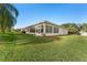 Backyard view of home with a screened-in patio and lush green grass at 13195 Se 93Rd Cir, Summerfield, FL 34491