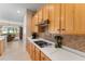 Kitchen with light wood cabinets, cooktop, and view into living room at 13195 Se 93Rd Cir, Summerfield, FL 34491