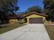 Ranch style home with a brown garage door and a long driveway at 611 Sw Shorewood Dr, Dunnellon, FL 34431
