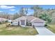 Single-story home with a light-brown facade, two-car garage, and landscaped lawn at 5370 Sw 85Th Ln, Ocala, FL 34476