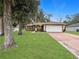 Tan house with white garage door, landscaping, and a paved driveway at 7090 Se 124Th Ln, Belleview, FL 34420