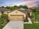 Tan house with a two-car garage and landscaped lawn at 7732 Sw 94Th Cir, Ocala, FL 34481