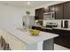 Modern kitchen with dark cabinetry, island, and stainless steel appliances at 9997 Se 161St Lane Rd, Summerfield, FL 34491