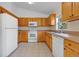 L-shaped kitchen with wood cabinets and white appliances at 3648 Sw 131St Place Rd, Ocala, FL 34473