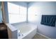 Relaxing bathroom featuring a large garden tub, tile flooring, and a window at 8457 Sw 138Th Pl, Ocala, FL 34473