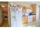 Kitchen with wood cabinets, white appliances, and a view into the laundry room at 8457 Sw 138Th Pl, Ocala, FL 34473