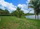 Lakefront property with lush lawn and tropical plants at 1235 Odoniel S Loop, Lakeland, FL 33809