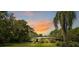 Ranch-style home with a metal roof, nestled on a lush, tree-lined lot at sunset at 6168 Arborea Dr, Lake Wales, FL 33898