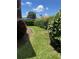Small, grassy backyard with hedges and a paved pathway at 680 Augusta Rd, Winter Haven, FL 33884