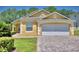 Charming yellow house with a white garage door and a brick paver driveway at 1608 Forest Hills Ln, Haines City, FL 33844