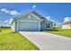 Newly built home with a light green exterior, two-car garage, and well-manicured lawn at 4073 Tullamore Ln, Auburndale, FL 33823