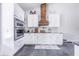 Modern white kitchen with granite countertops and a rustic wood vent hood at 12510 Lake Hatchineha Rd, Haines City, FL 33844