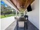 Covered patio with wood ceiling, outdoor furniture, and a large TV at 12510 Lake Hatchineha Rd, Haines City, FL 33844