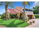 House exterior showcasing a red tile roof, lush landscaping, and a spacious lawn at 4 Casarena Ct, Winter Haven, FL 33881